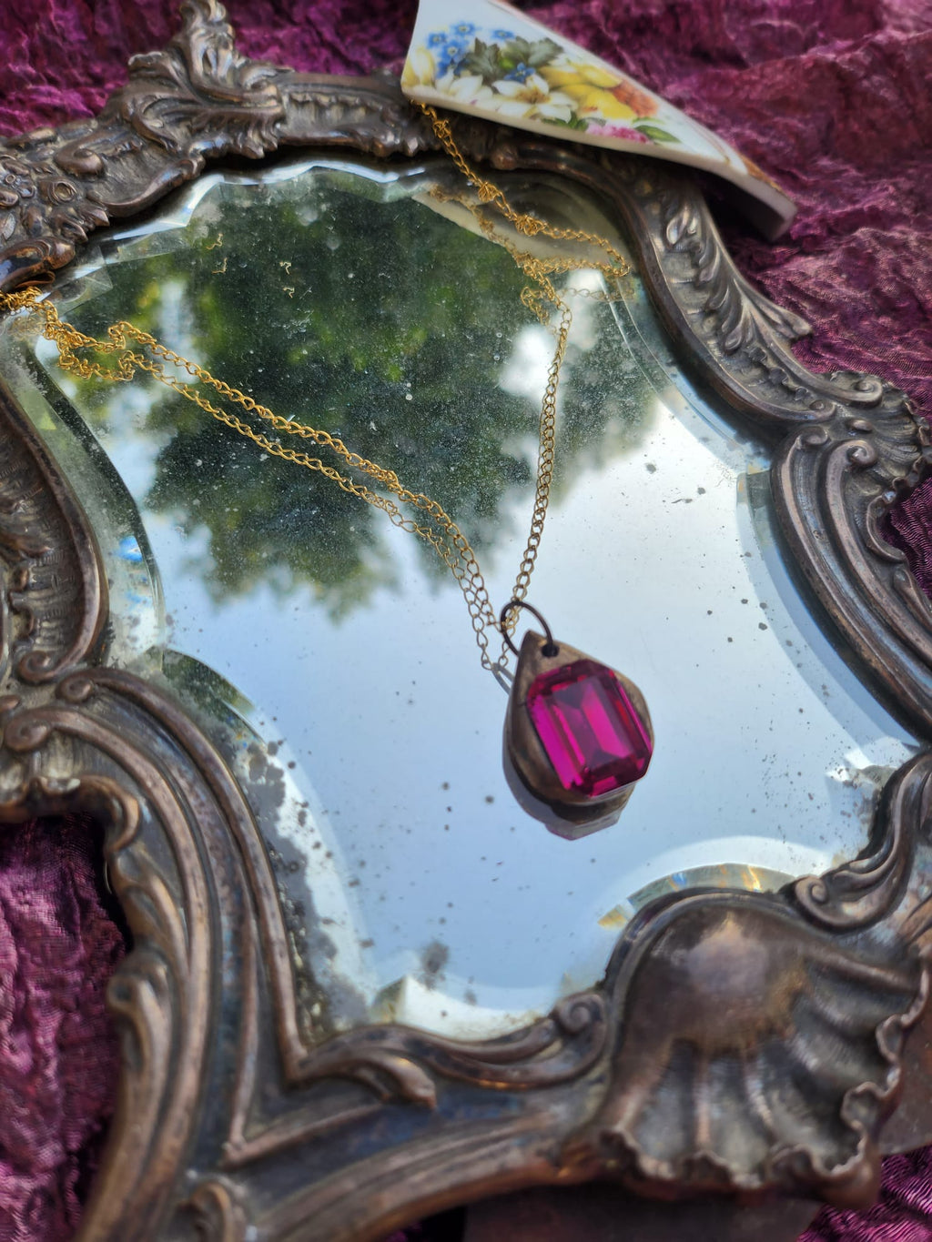 Colgante de bronce hecho a mano con cristal fucsia.