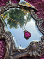 Colgante de bronce hecho a mano con cristal fucsia.