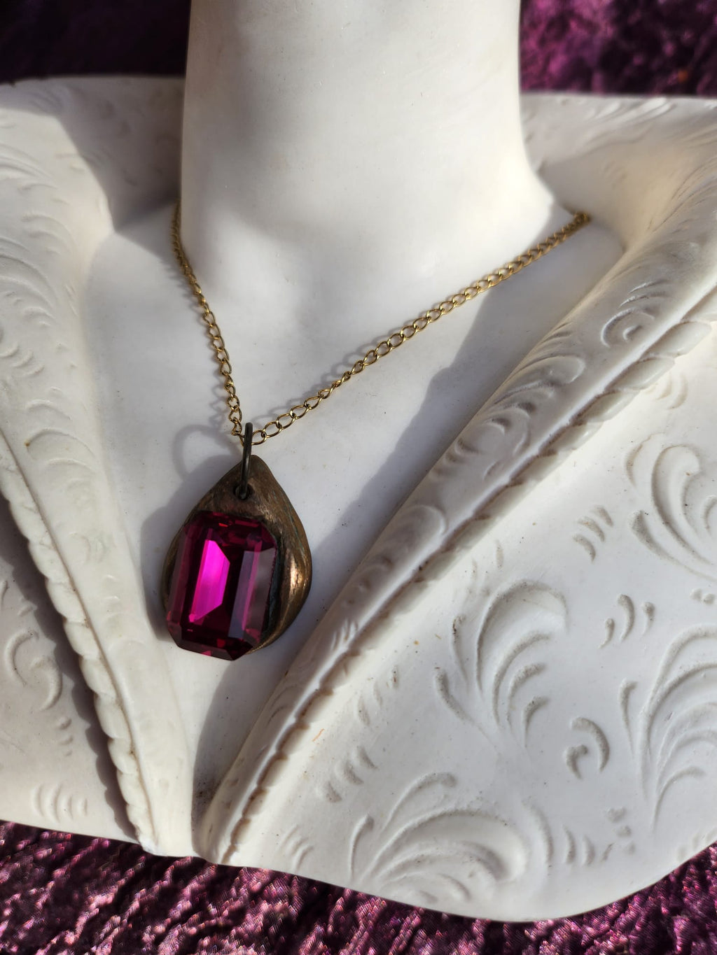 Colgante de bronce hecho a mano con cristal fucsia.