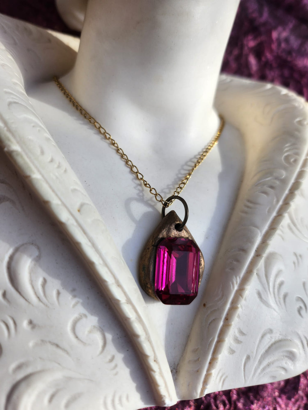 Colgante de bronce hecho a mano con cristal fucsia.