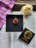 Colgante de bronce hecho a mano con cristal rojo intenso.